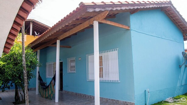 A two-story house with a blue exterior, white window frames, and a tiled patio. - Casa Pet Friendly a 950m da Praia Vista Linda (Bertioga)