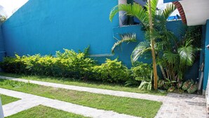 A blue building with a paved pathway and lush greenery. - Casa Pet Friendly a 950m da Praia Vista Linda (Bertioga)