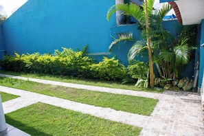 A blue building with a paved pathway and lush greenery. - Casa Pet Friendly a 950m da Praia Vista Linda (Bertioga)