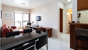 Habitación de hotel con comedor, televisor montado en la pared y kitchenette.