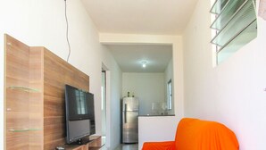 Ett modernt vardagsrum med en TV-möbel i trä, en platt-TV och en orange soffa.