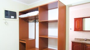 Una habitación con un armario de madera, piso de baldosas y una zona de cocina con armarios de madera.