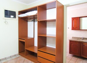 A room with a wooden wardrobe, a tiled floor, and a kitchen area with wooden cabinets. - Apto a 600 metros da Praia Grande, em Ubatuba/SP (Ubatuba)