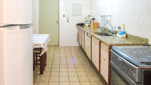 Una cocina compacta con refrigerador, estufa, lavamanos y una zona de comedor con mesa y sillas.