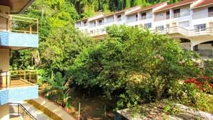 Un hotel de varios pisos, rodeado de abundante vegetación y un pequeño cuerpo de agua.