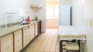 Una cocina compacta con un lavamanos, estufa y una mesa con mantel floreado.