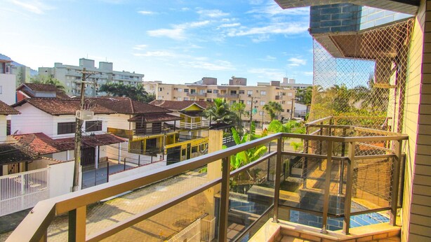 Zona residencial con varios edificios, un balcón con barandilla de vidrio y vistas del vecindario circundante.