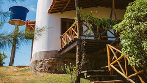 Ein traditionelles Gebäude mit weißer Fassade, rotem Ziegeldach und einer Holztreppe, die zu einer Veranda führt.