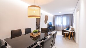 A modern dining area with a black table, wicker centerpiece, and a hanging light fixture. - Incrível apartamento com Wi-Fi na Praia Brava/SC (Itajaí)