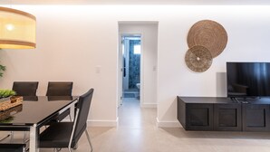 A modern living room with a dining area, a TV, and a decorative wall piece. - Incrível apartamento com Wi-Fi na Praia Brava/SC (Itajaí)