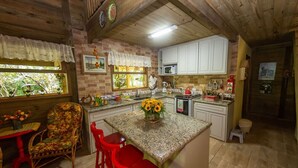 A kitchen with a central island, red bar stools, a microwave, and a sink.