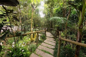A stone staircase surrounded by lush greenery and a wooden railing.