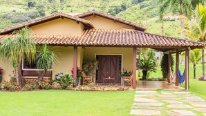 Une maison avec un toit en tuiles, une véranda et un chemin de pierre menant à l’entrée.
