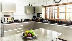 Une cuisine moderne dotée d’un plan de travail en granit, d’un four à micro-ondes, d’une machine à café et d’un saladier rempli de fruits.