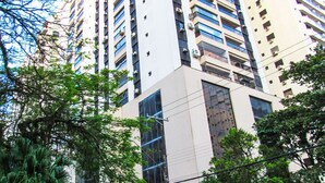 Un edificio alto con varios pisos, ventanas grandes y fachada de piedra.