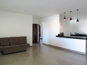 A spacious living area with a sofa, a kitchen counter with appliances, and pendant lighting. - Casa com Piscina e Área Gourmet | Taipu de Fora (Maraú)