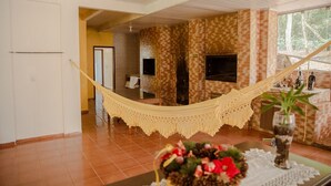 Una habitación amplia con una hamaca, chimenea y vistas a árboles.