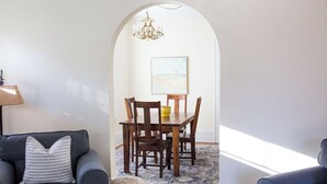 Ein Essbereich mit Holztisch und Stühlen, einer Chandelüster und einem Gemälde an der Wand.