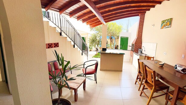 Un ampio patio con tavolo e sedie in legno, un angolo cottura e una scala che conduce a un livello superiore.