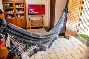 Eine Hängematte in einem Zimmer mit Fernseher, Holzschrank und Fliesenboden.