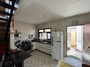 Eine Küche mit Mikrowelle, Herd und Kühlschrank. Ein Fenster und eine Tür führen nach draußen.