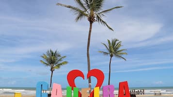 Une plage bordée de palmiers, avec une pancarte sur laquelle on peut lire le mot « CAUTURA », les lettres étant formées de cœurs.