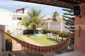 A hammock in a backyard with a pool, a white fence, and a palm tree. - Casa de andar a 200m da areia -Praia da Caueira/SE (Itaporanga D'Ajuda)