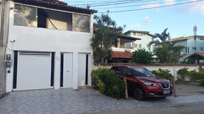 Ein zweistöckiges Gebäude mit Garage, ein rotes Auto davor und bewölkter Himmel.