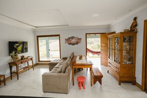 Un salon spacieux avec un canapé beige, une table à manger en bois et un buffet aux portes vitrées.