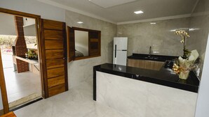 Una cocina moderna con encimera negra, refrigerador blanco y puerta de madera.