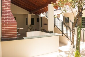 Um interior moderno com cozinha, escada e um pequeno espaço ao ar livre com uma árvore.