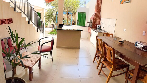 En rummelig terrasse med et træbord og stole, en lille ø med en vask, og en trappe op til en etage.