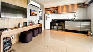 Una cucina moderna con schermo piatto, forno integrato e zona pranzo con sgabelli.