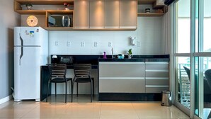 Una cucina moderna con frigorifero, forno a microonde e due sedie.