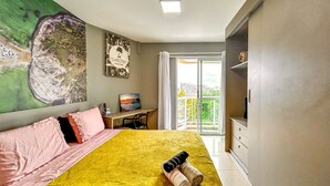 Una camera d'albergo con un letto, una scrivania, una sedia, una televisione e un balcone con vista.