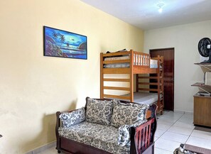 A room with a bunk bed, a sofa, a desk, and a painting on the wall. - Casa c churrasqueira próx à Praia Jardim Real/SP (Praia Grande)