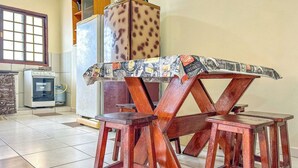 Un coin repas avec une table et des tabourets en bois, un réfrigérateur et une fenêtre.