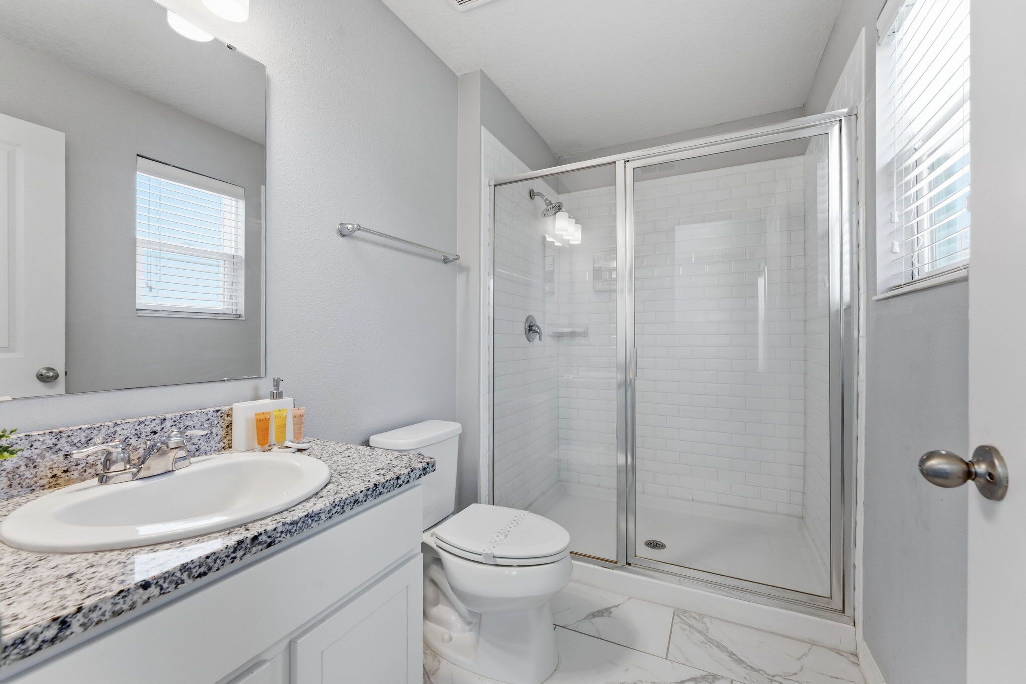 A bathroom with a white sink, toilet, and glass-enclosed shower.