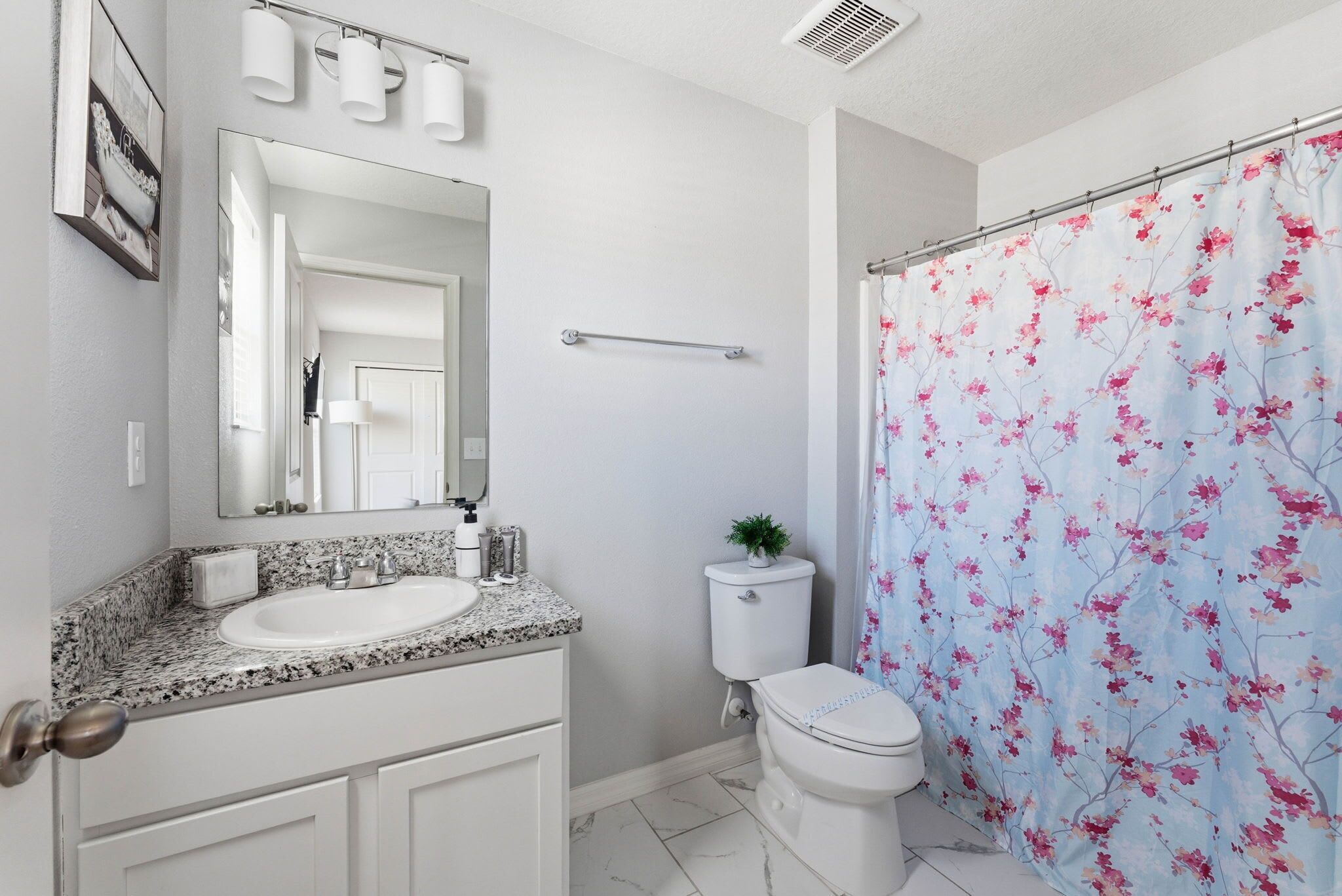 A bathroom with a white sink, mirror, and toilet.