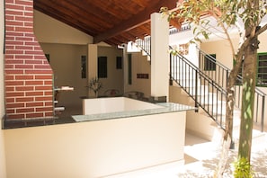 Um interior moderno com cozinha, escada e um pequeno espaço ao ar livre com uma árvore.
