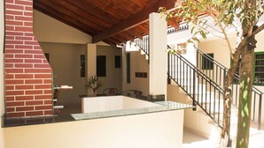 A spacious indoor area with a brick wall, a staircase, and a potted plant. - Apto Aconchegante c Wi-Fi, Churrasq e Pet Friendly (Campo Grande)