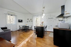 Eine moderne Küche mit einer Wand aus Wortwolken, ein Essbereich mit Tisch und Stühlen sowie ein graues Sofa.