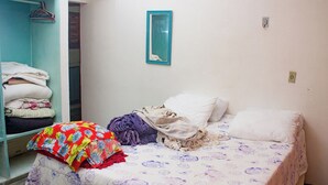 Una habitación pequeña y sencilla con una cama, un armario y un espejo fijado a la pared.
