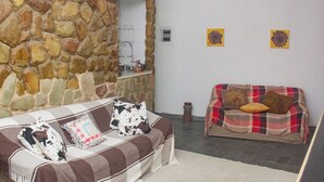 Una sala de estar con pared de piedra, dos sofás y una mesita con espejo.