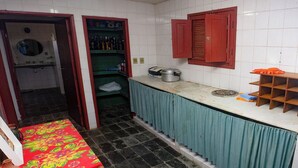 Una cocina con salpicadero de azulejos, una encimera con fregadero y una ventana con contraventanas rojas.