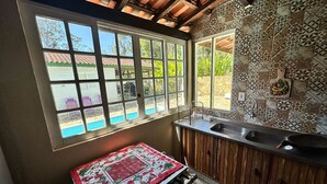 Una cocina con ventana, un lavamanos y un salpicadero de azulejos.
