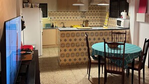 Una cocina con isla central, techo de madera y zona de comedor con mesa y sillas.