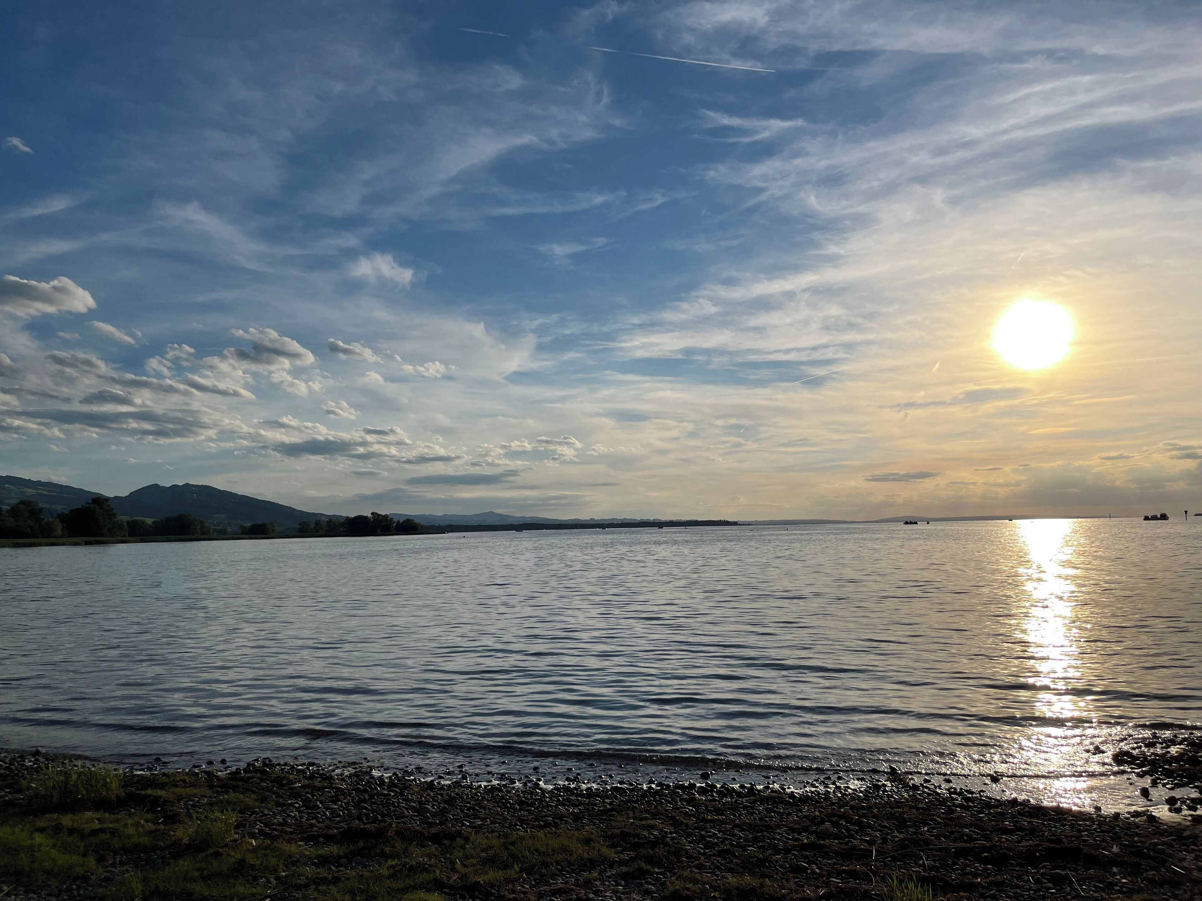 Un lac paisible, avec un ciel dégagé et des montagnes à l'horizon.
