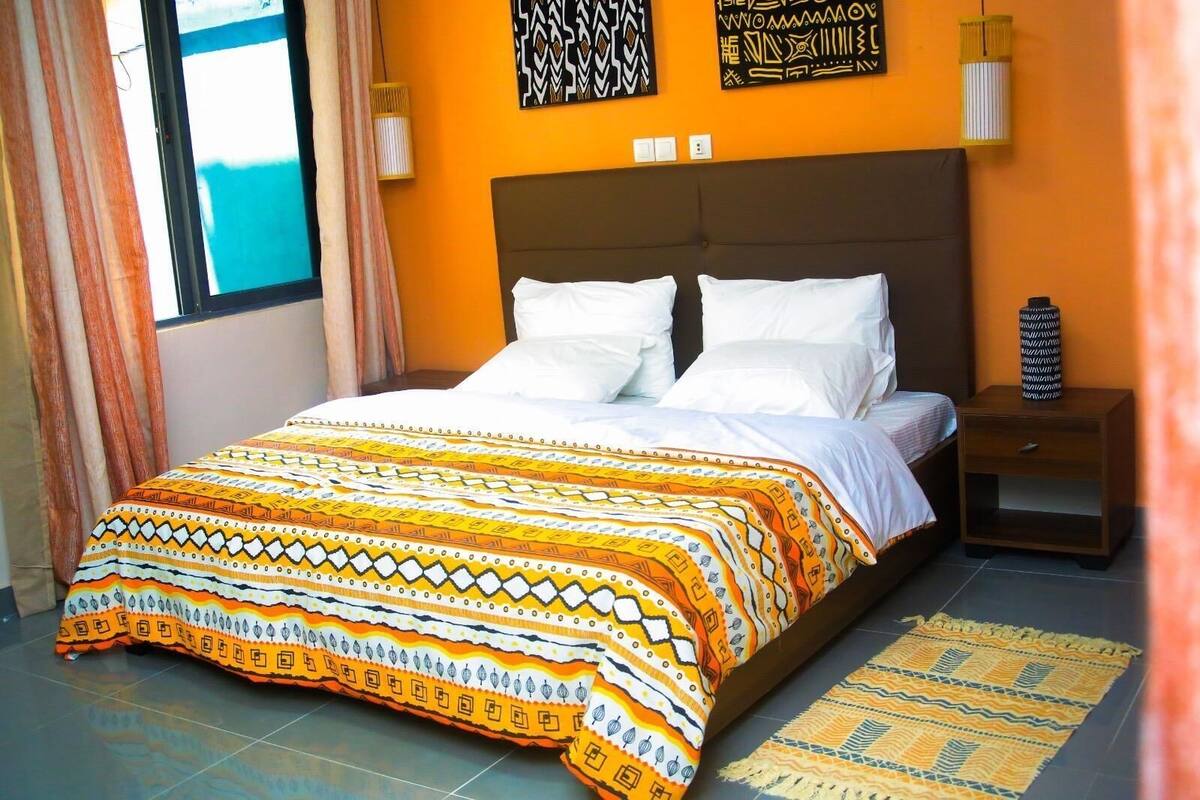 A bedroom with a bed, a nightstand, a lamp, and patterned curtains.