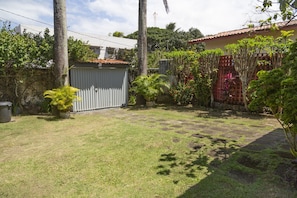 Patio trasero residencial con área cercada, un cobertizo pequeño y varias plantas.